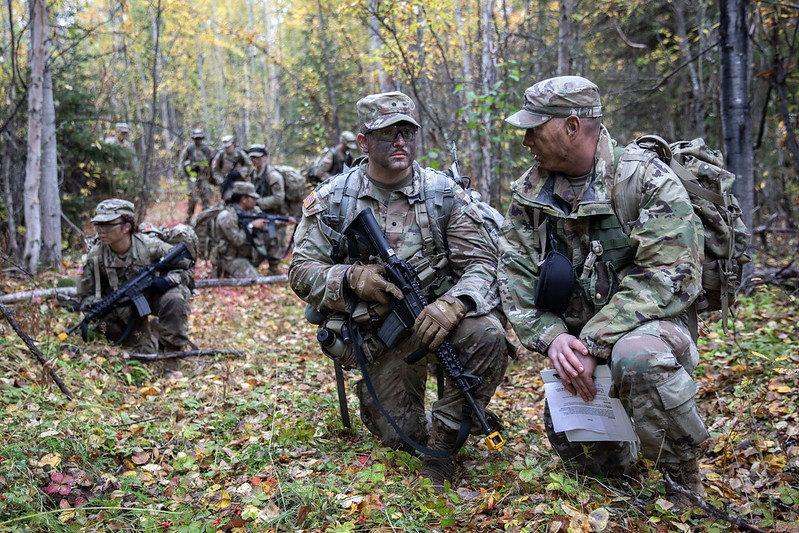 Soldiers kneel together in conversation in the forest 