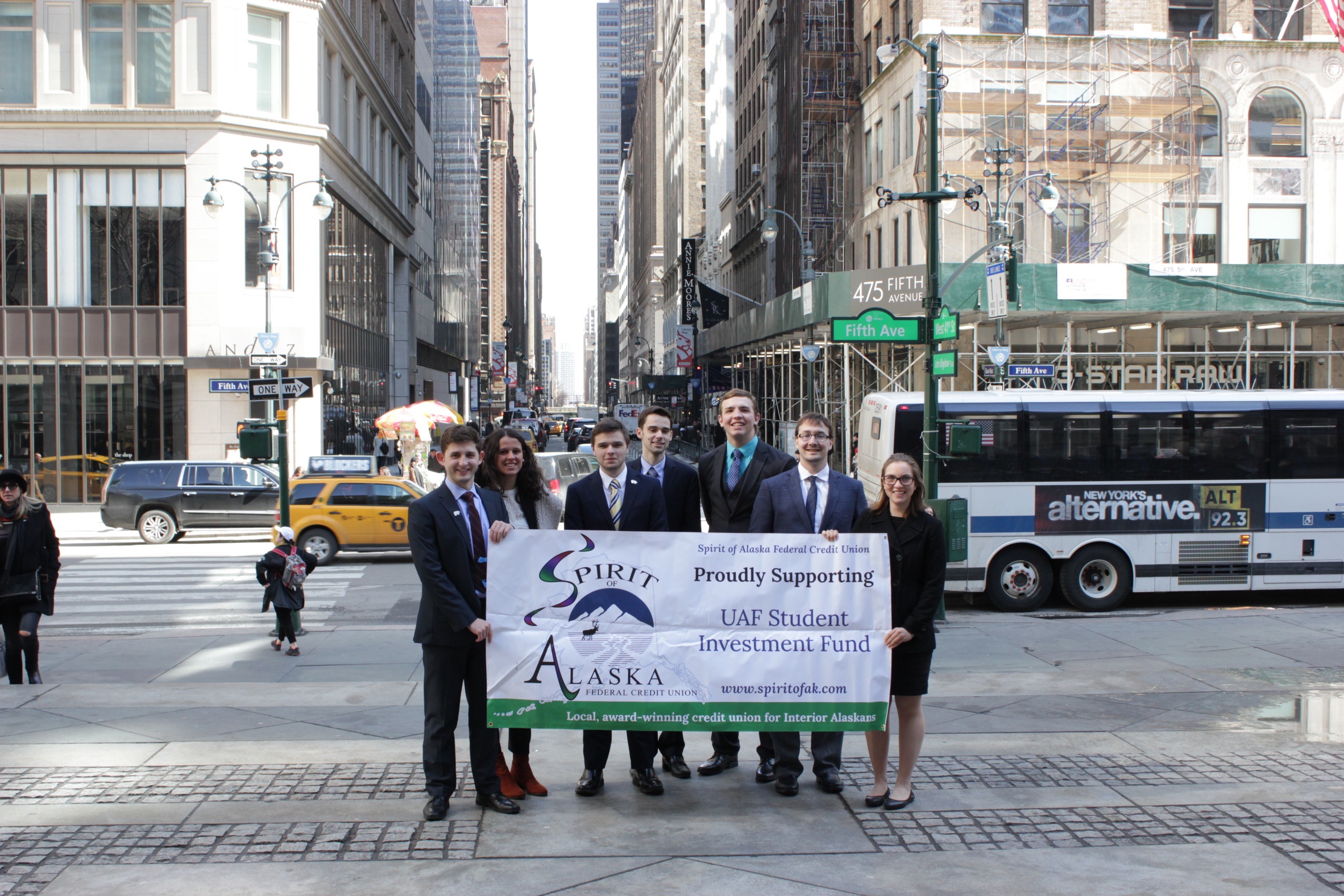 seven students smile on a busy street in New York City holding banner that reads Spirit of Alaska proudly supports UAF Student Investment Fund