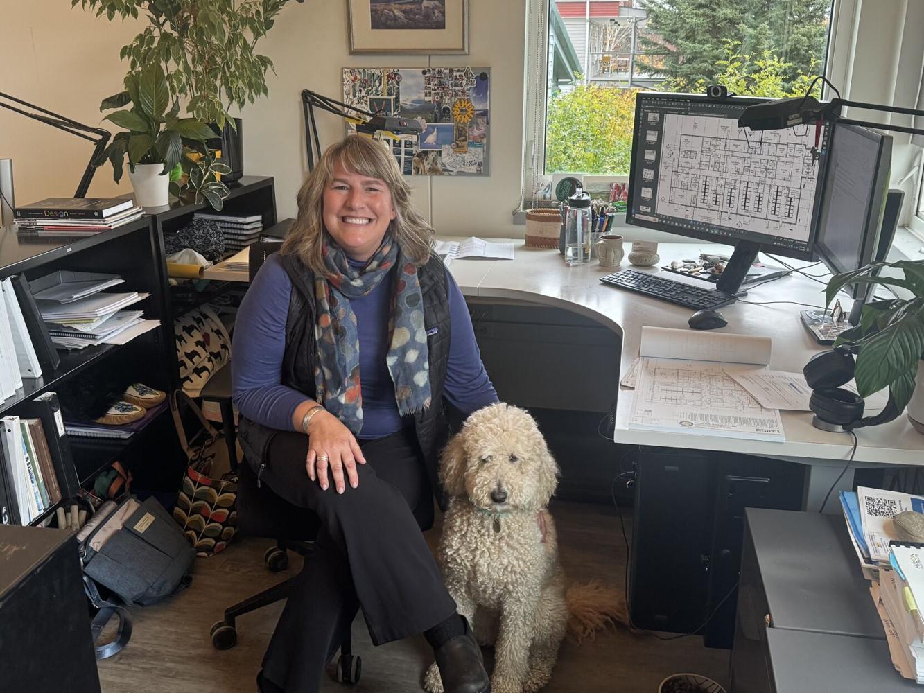 woman poses with labradoodle in her office