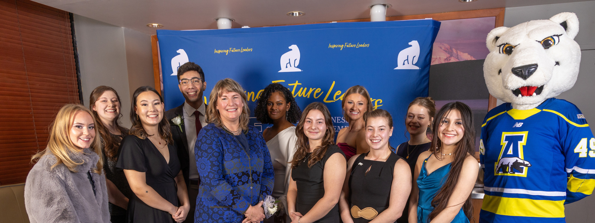 students smile at photobooth with UAF mascot