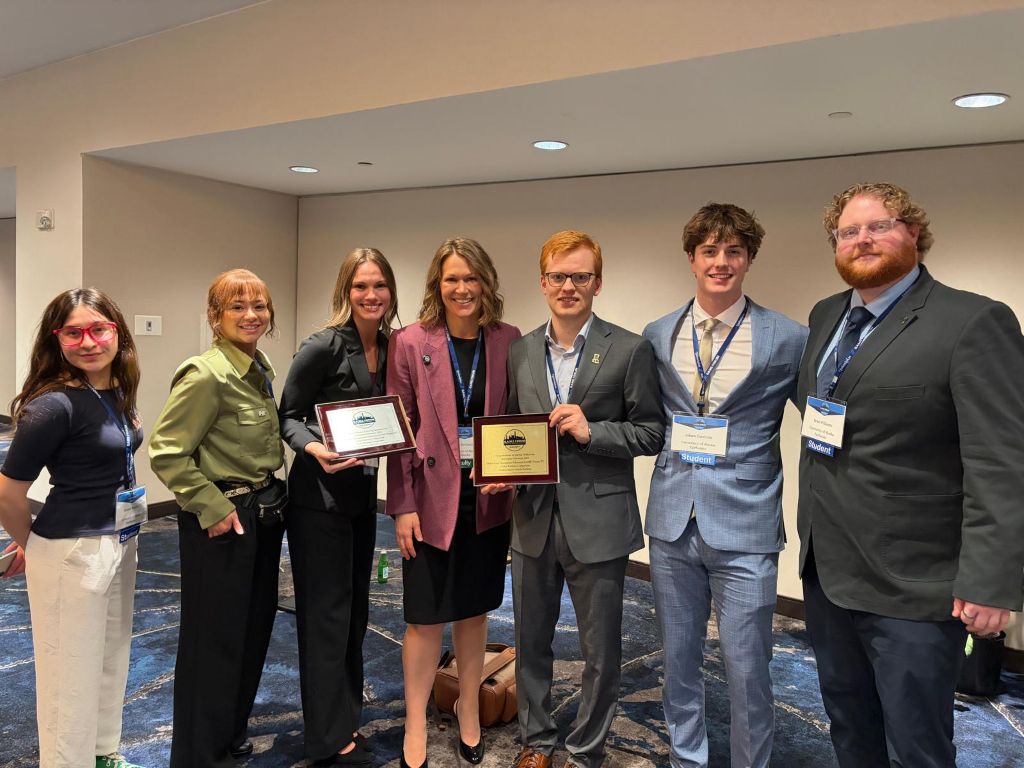 Students standing with Dr. Kim McGinnis with awards earned a the global asset management education forum.
