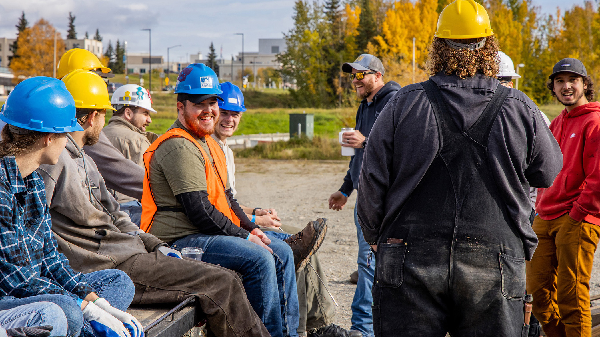 Group of cheerful students wearing hard hats and workwear taking a break