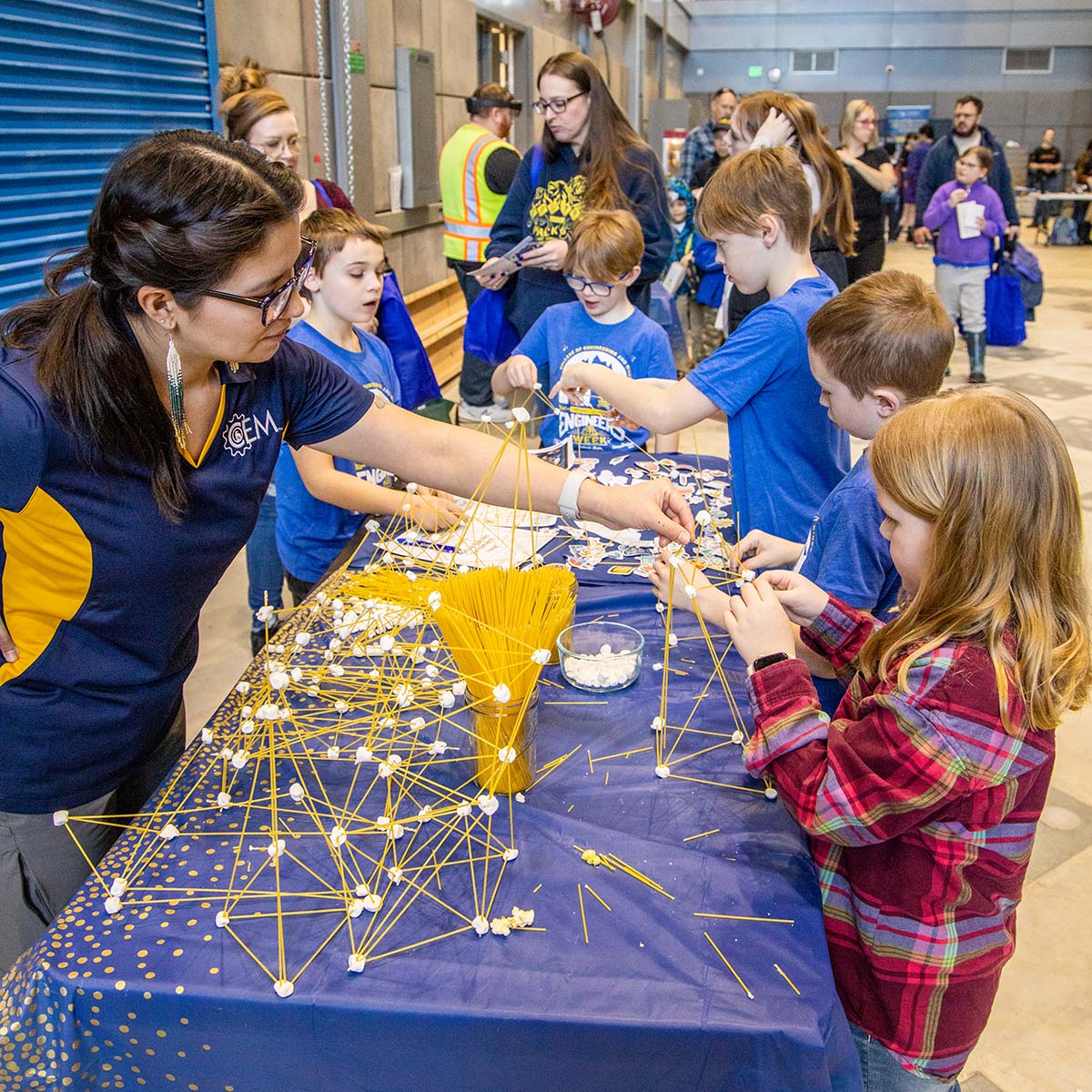 CEM student is building spaghetti marshmallow structures with kids visiting the 2024 Engineering Open House