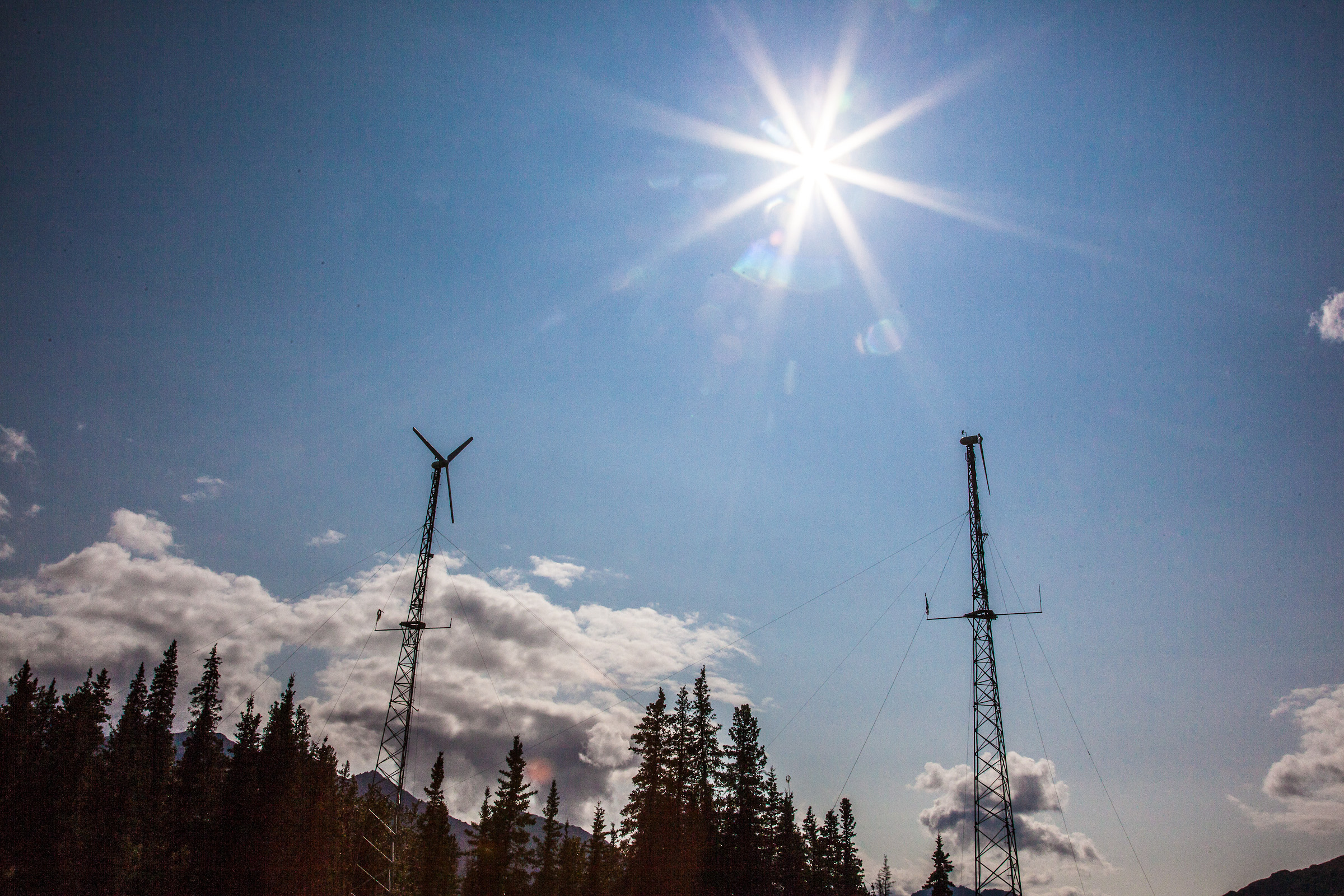 Wind turbine in the distance with backdrop of bluesky and a bright sun