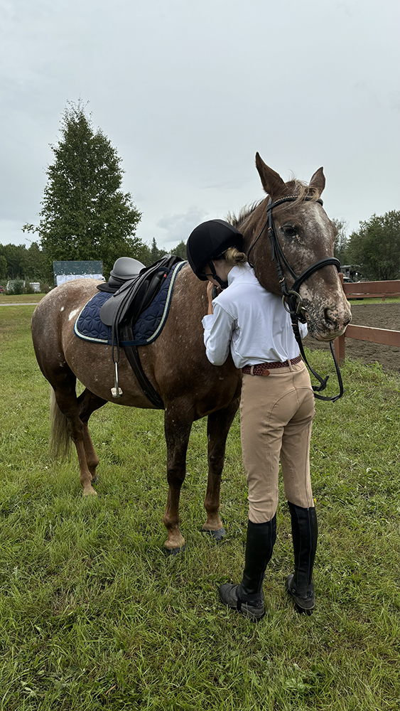 Girl standing next to horse