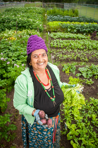 Bhakti Dhakal shows off some of the produce grown for Fresh International Gardens. Photo by Edwin Remsberg