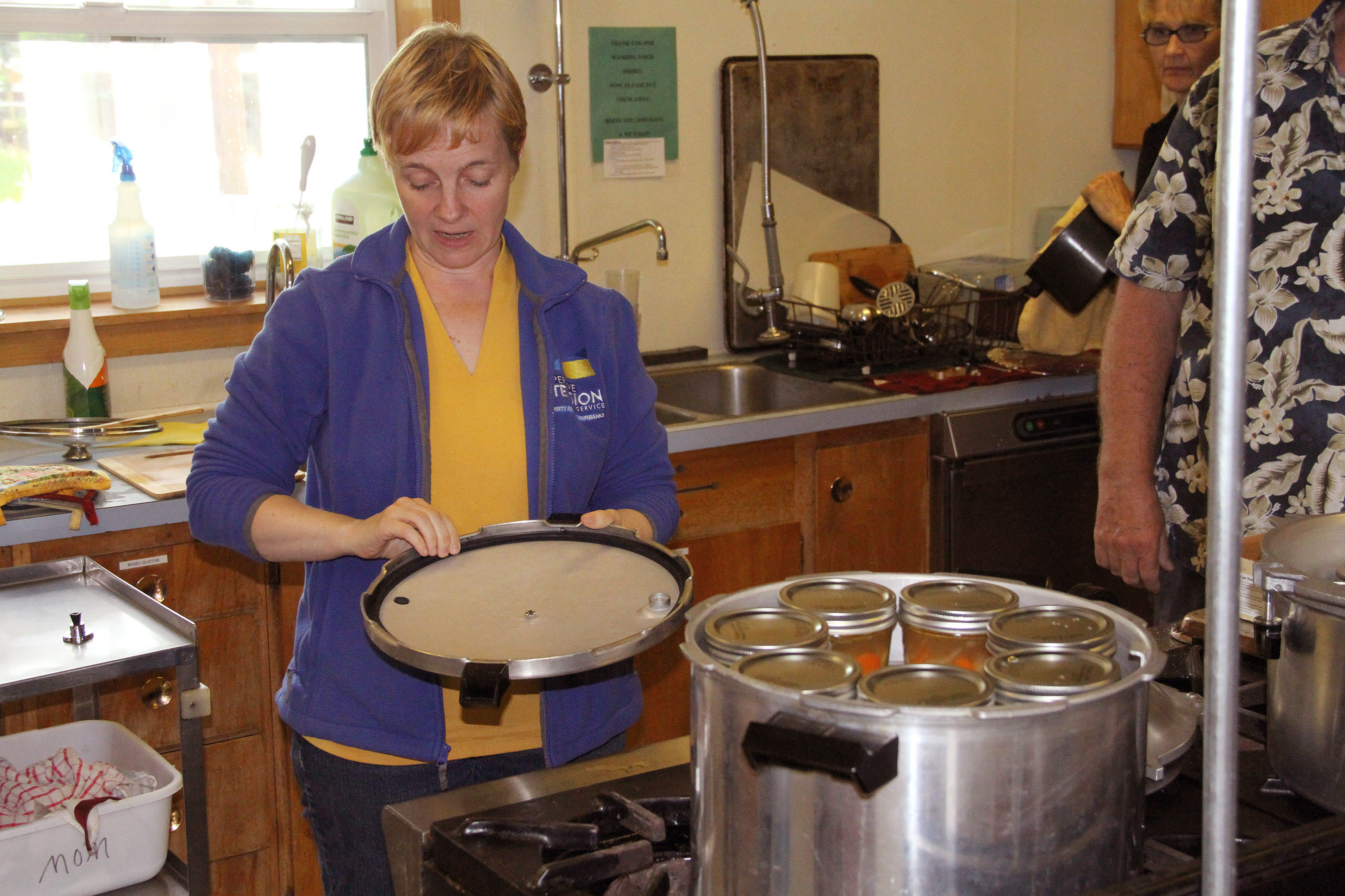 Sarah Lewis teaches a Sitka canning class how to put on a pressure canner lid and make sure the vent is clear and the gasket undamaged. She was canning soups and sauces. Photo by Charles Bingham for the Sitka Kitch