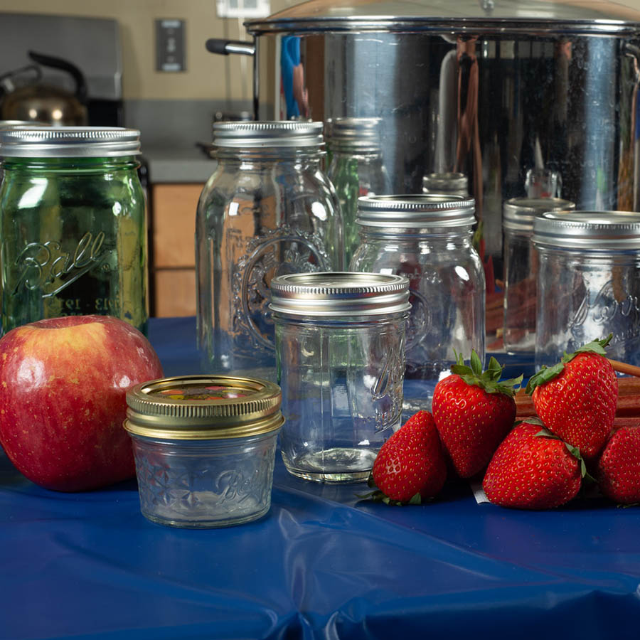 Table with a arrangement of jars and fruit on it