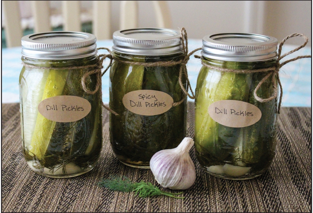Three jars of green vegetables next to garlic