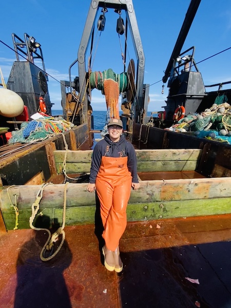Student in fish gear standing on deck of small trawl vessel Photo of student in fish gear standing on deck of a small trawl vessel