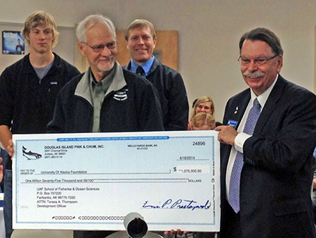 A board member of Douglas Island Pink and Chum (DIPAC) presents a $1,075,000 check to UAF Chancellor Brian Rogers for a fellowship endowment. Student recipient Casey McConnell and UAF Juneau Fisheries Center Director Keith Criddle stand in the background. Photo by Alex Wertheimer.