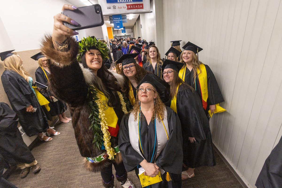 Lynette Hepa, left, takes a selfie photo with fellow graduates during the University of Alaska Fairbanks 2023 Commencement Ceremony at the Carlson Center Saturday, May 6, 2023. Hepa received her B.A. in Social Work; Psychology. | UAF Photo by Eric Engman