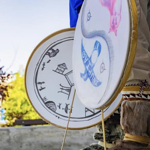 A Native Alaskan drummer in boots holds drums down by his sides. UAF photo by Leif Van Cise