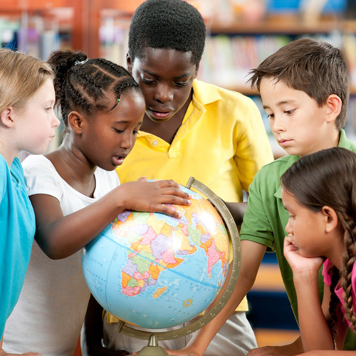 A group of elementary school children examine a globe. Photo courtesy of Canva.