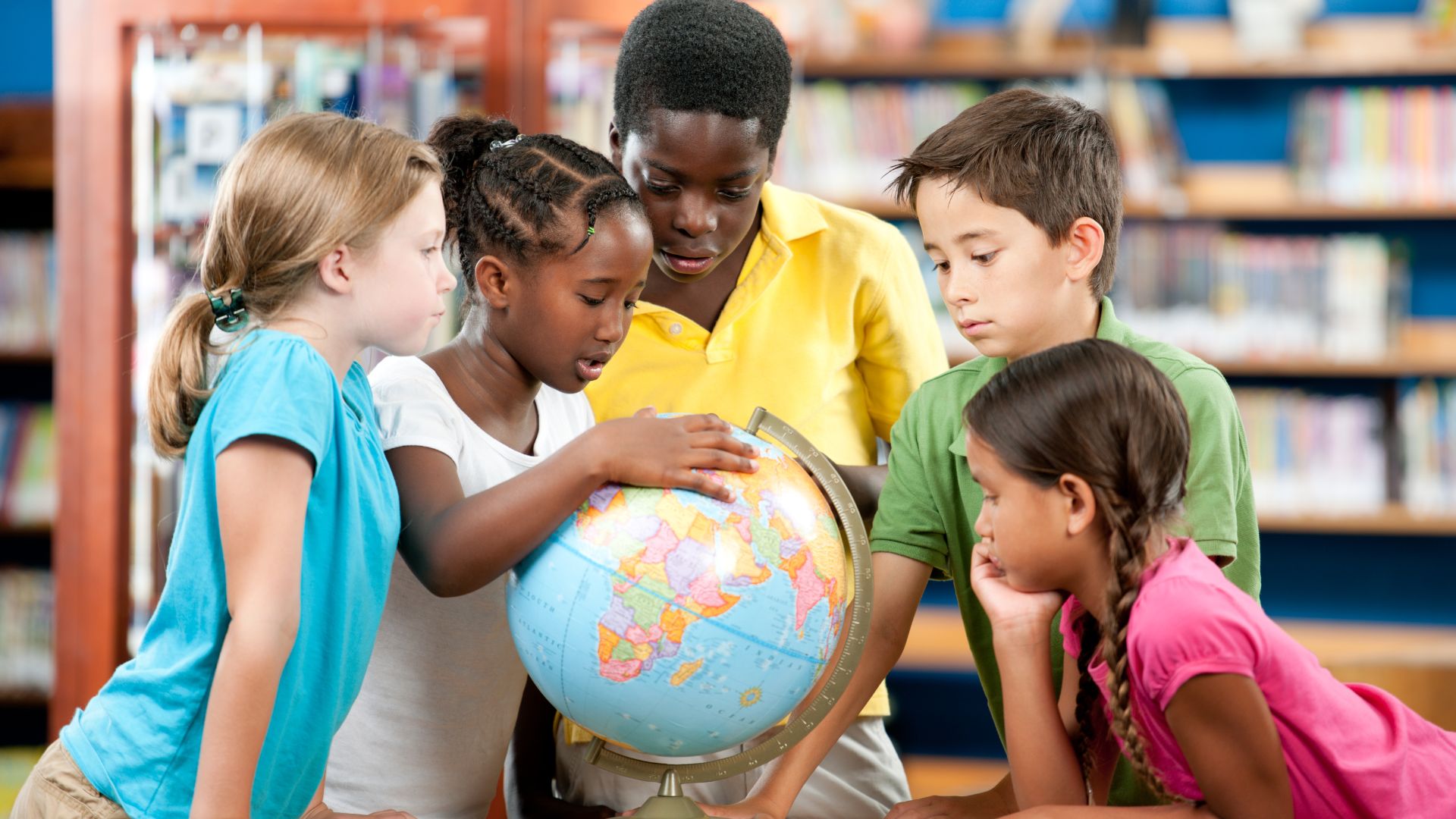 Elementary school students examine a globe. Photo courtesy of Canva