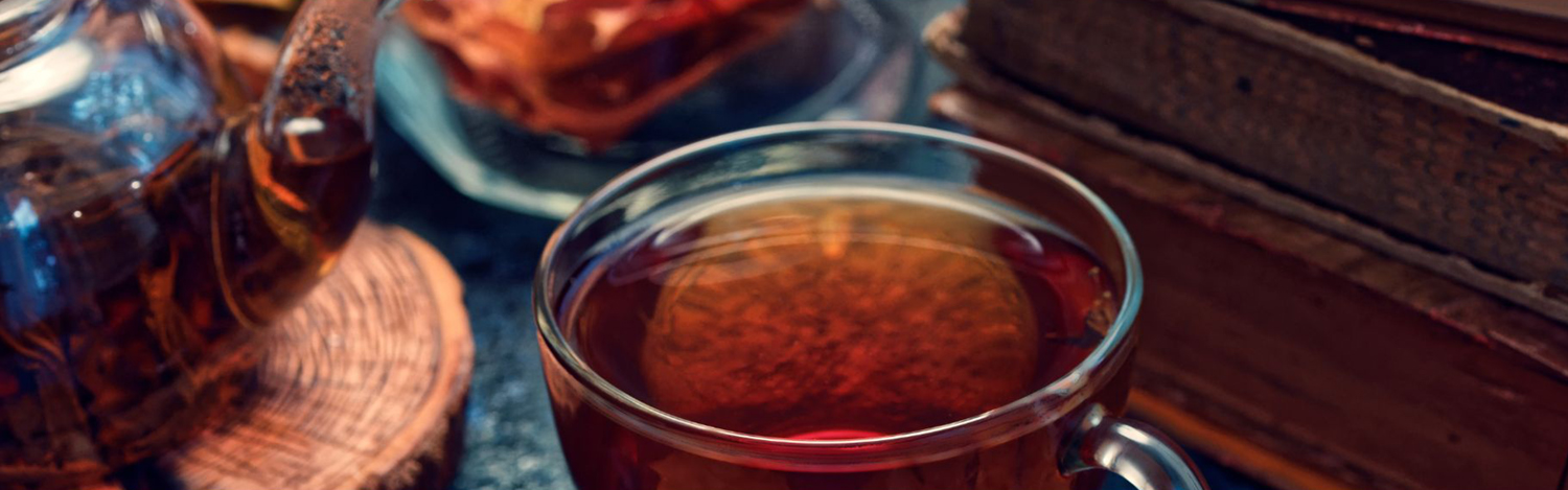 Tea cup and kettle next to a stack of books. Image courtesy of Canva