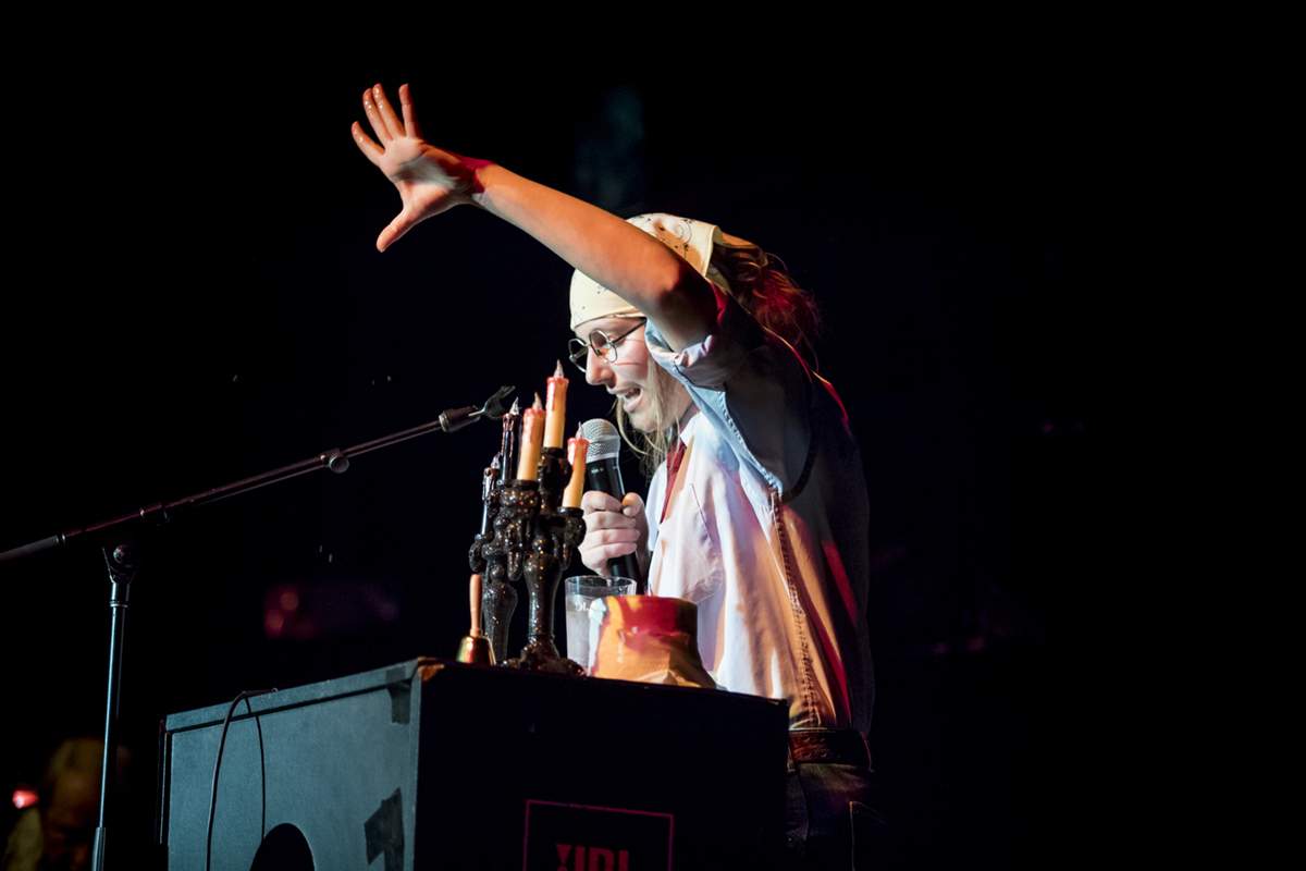 Brandi Jo Nyberg flicks water from a plastic cup onto the audience during a reading at the 28th annual 2018 Dead Writers event hosted by the UAF English department on Friday, October 26th, 2022 at the Blue Loon. UAF Photo by Sarah Manriquez