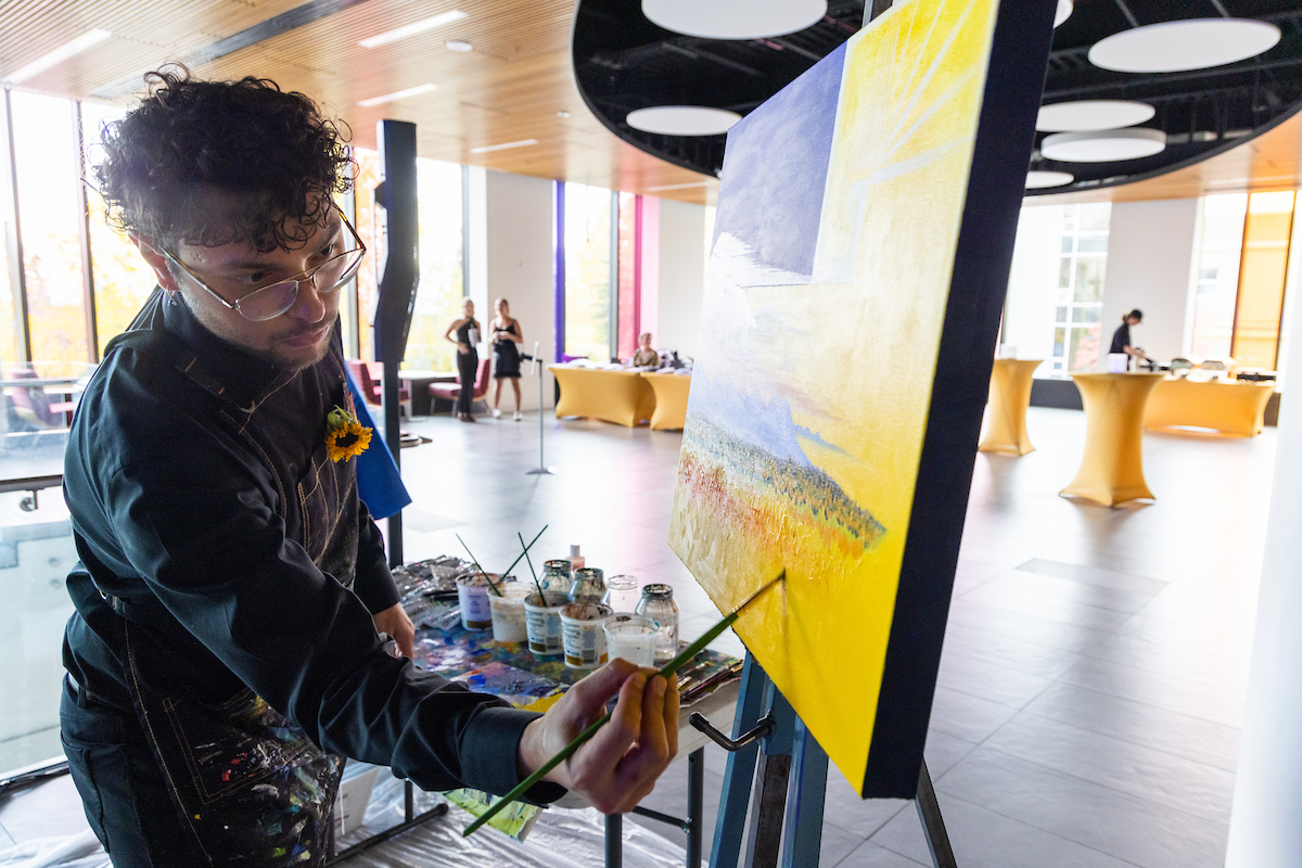 Kyle Agustines puts the finishing touches on his painting that was auctioned off at the Blue & Gold Banquet and Fundraising Auction at Dine 49 on the UAF campus Saturday, September 14, 2024. UAF Photo by Eric Engman