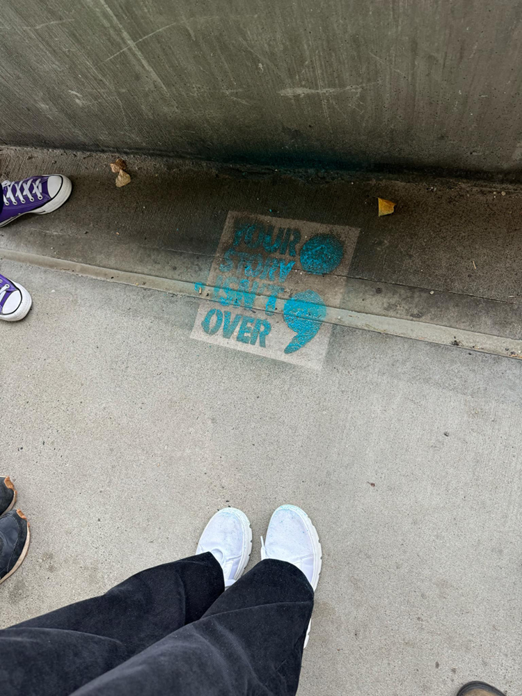 "Your story isn't over" with a semicolon, stenciled onto the UAF campus concrete walkway. UAF Photo by Jamie Haman