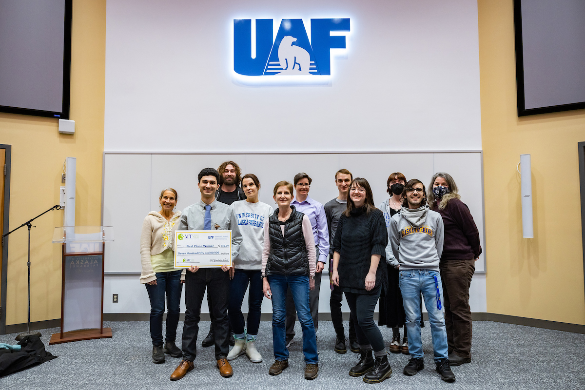 First place 3MT winner Aaron Salzman poses with CLA faculty, students and staff after bring presented with a check at the 2022 3MT competition. UAF Photo by Leif Van Cise