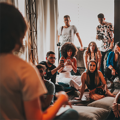 A group of people sit in an informal circle around  room focused on a speaker