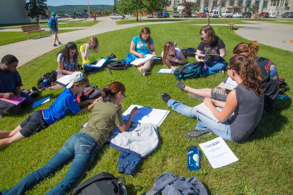 students studying outside in the grass in a circle
