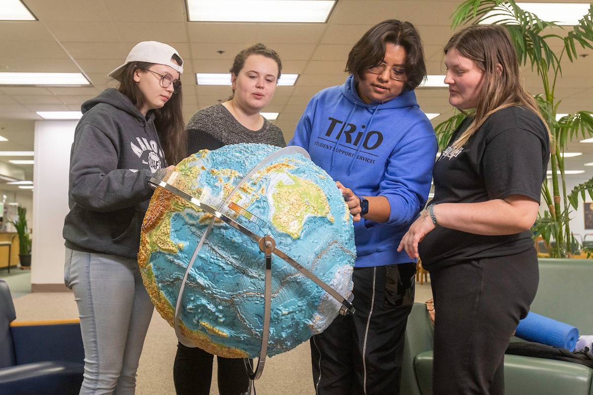 TRIO students looking at a globe together