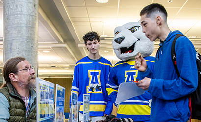 Students in UAF jerseys at career fair talking to a staff member. 