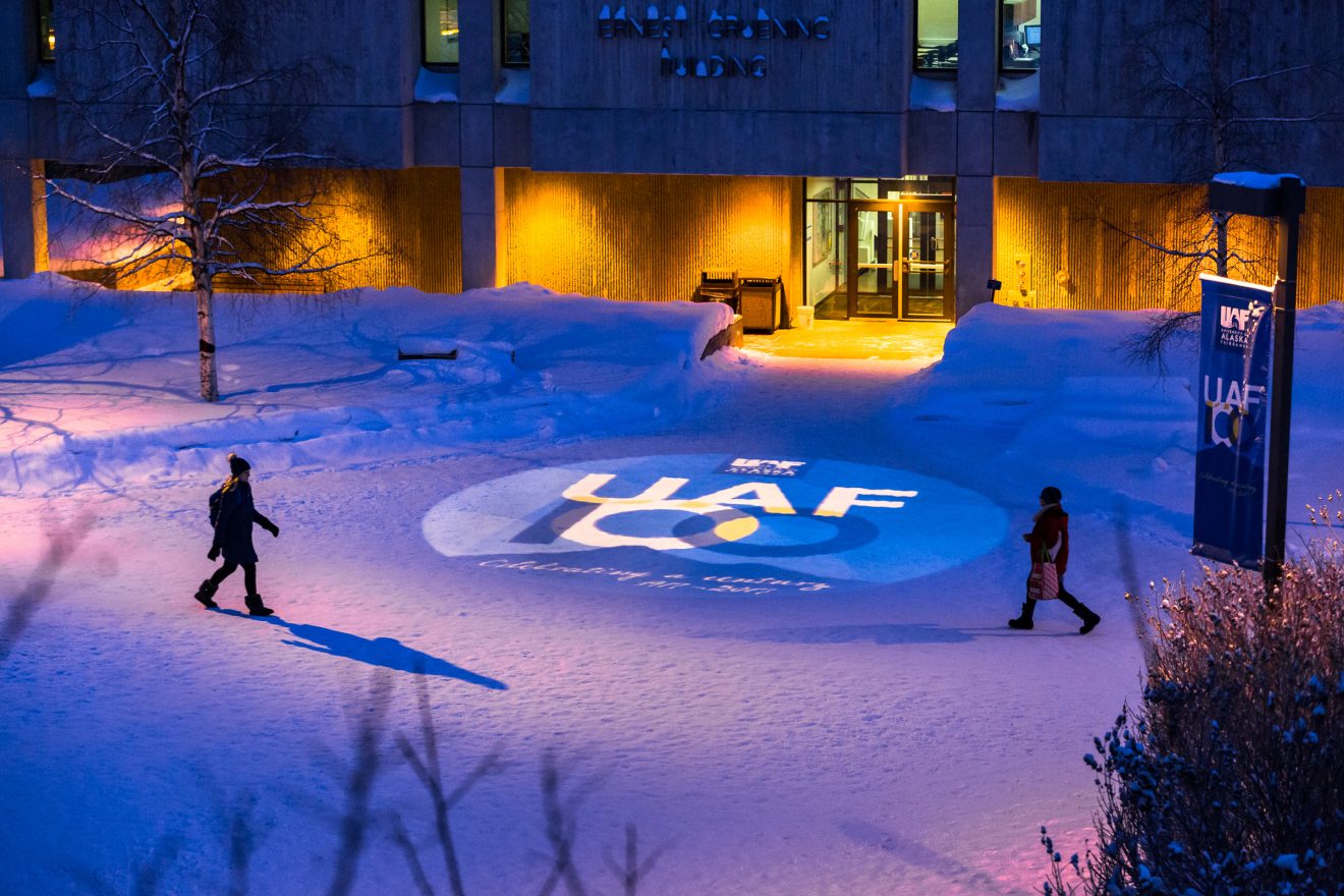 A projection of UAF's centennial logo decorates the walkway near the Gruening Building on the Fairbanks campus Friday, Jan. 20, 2017.