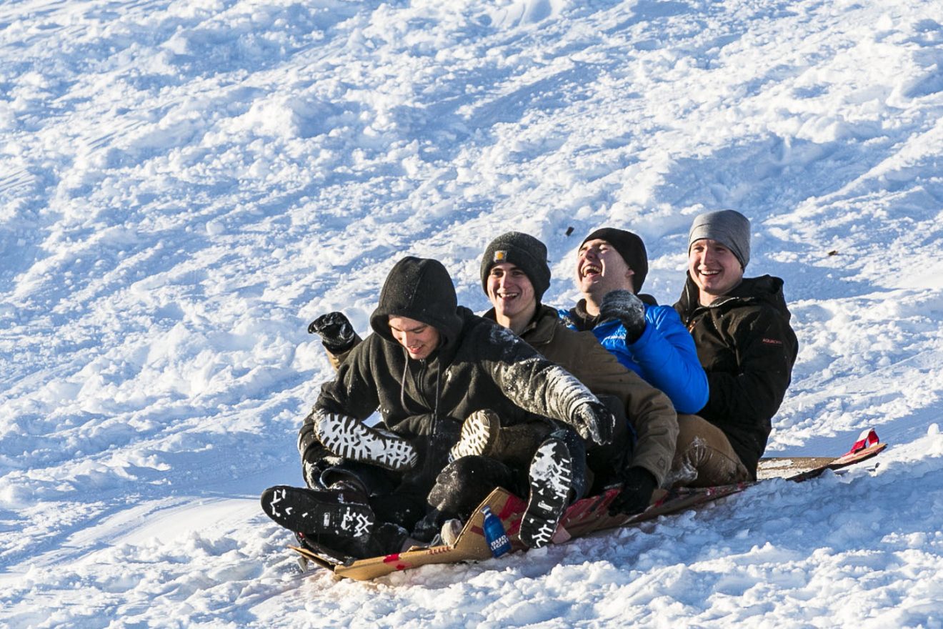 Students sledding down a hill.