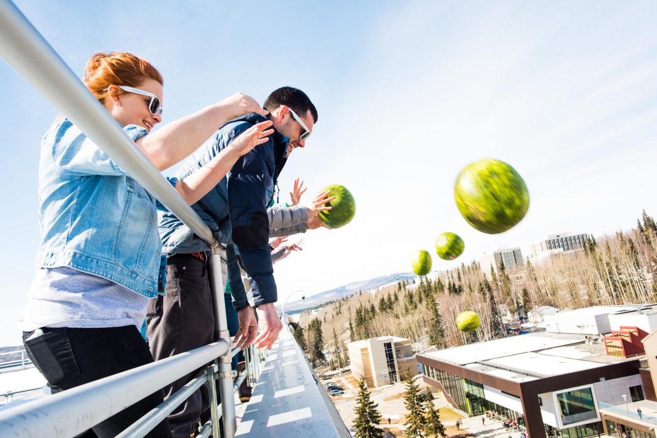 Nikki Crenshaw, left, and Brian Reggiani, right, along with other students launch a volley of watermelons from the roof of the Gruening Building during this year's SpringFest on Thursday, April 19, 2018.