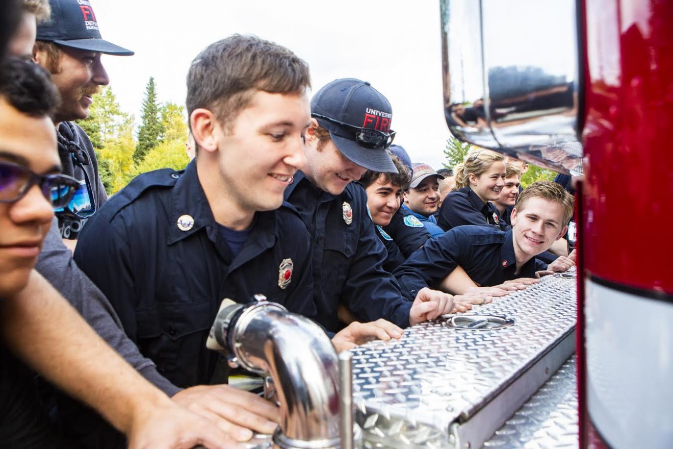 Student firefighters push a new firetruck into the fire station on the Fairbanks campus as part of the truck's commissioning ceremony.