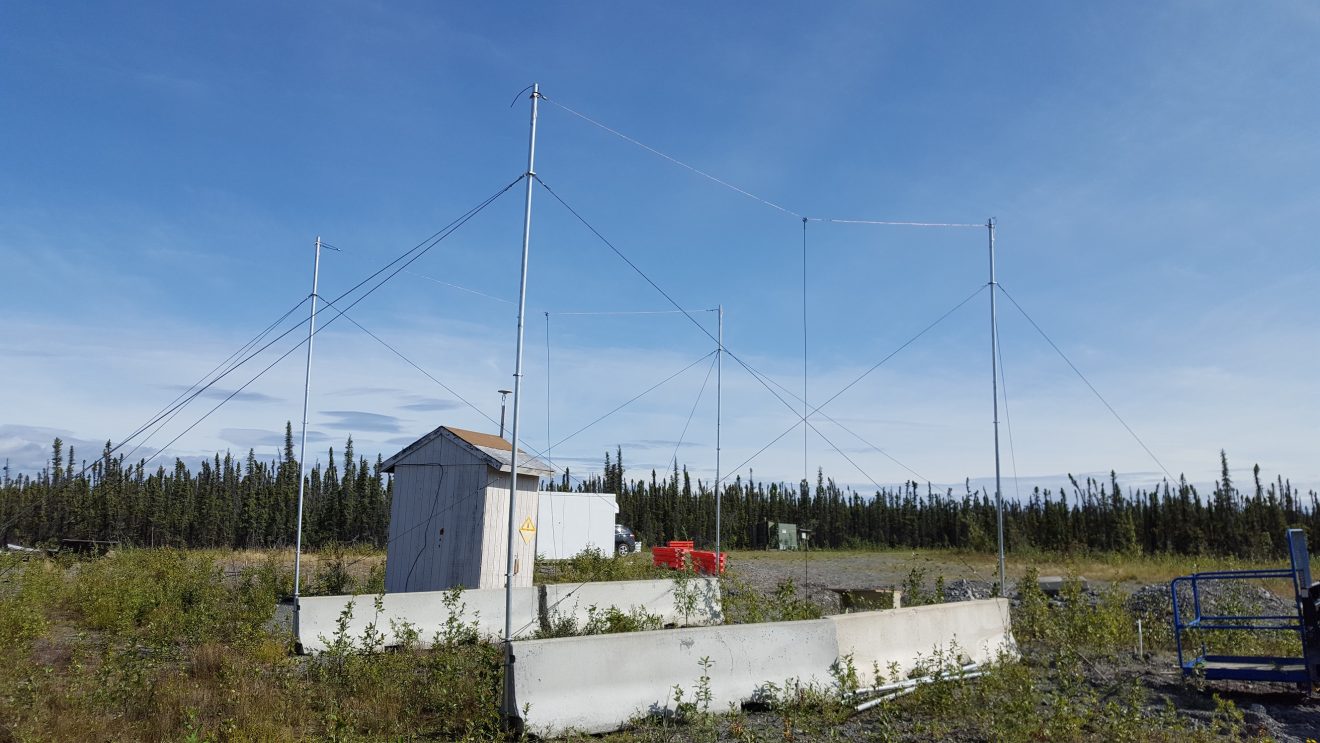HAARP photo of an antenna array over a small outbuilding in the taiga on a sunny summer day.