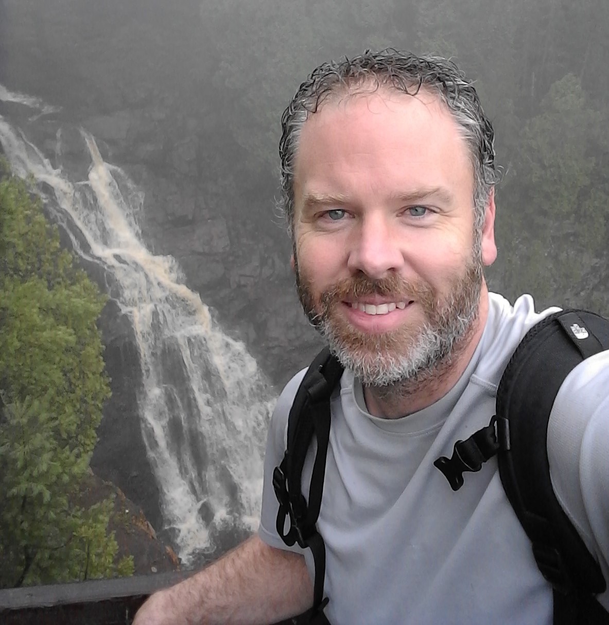 Shawn Crimmins standing in front of a waterfall.
