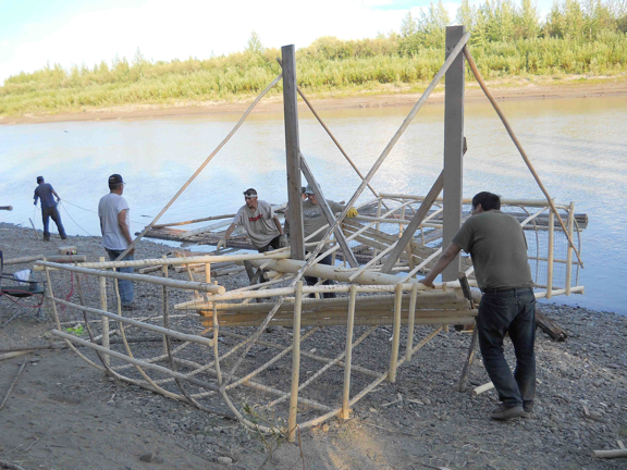 Men with fishwheel on the banks of a river.