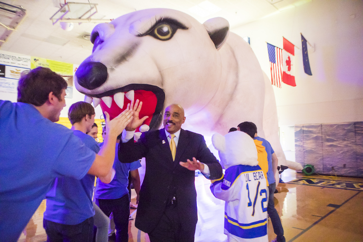 Keith Champagne high-fives several students. Little Nook is beside him, and a giant balloon polar bear is behind them.