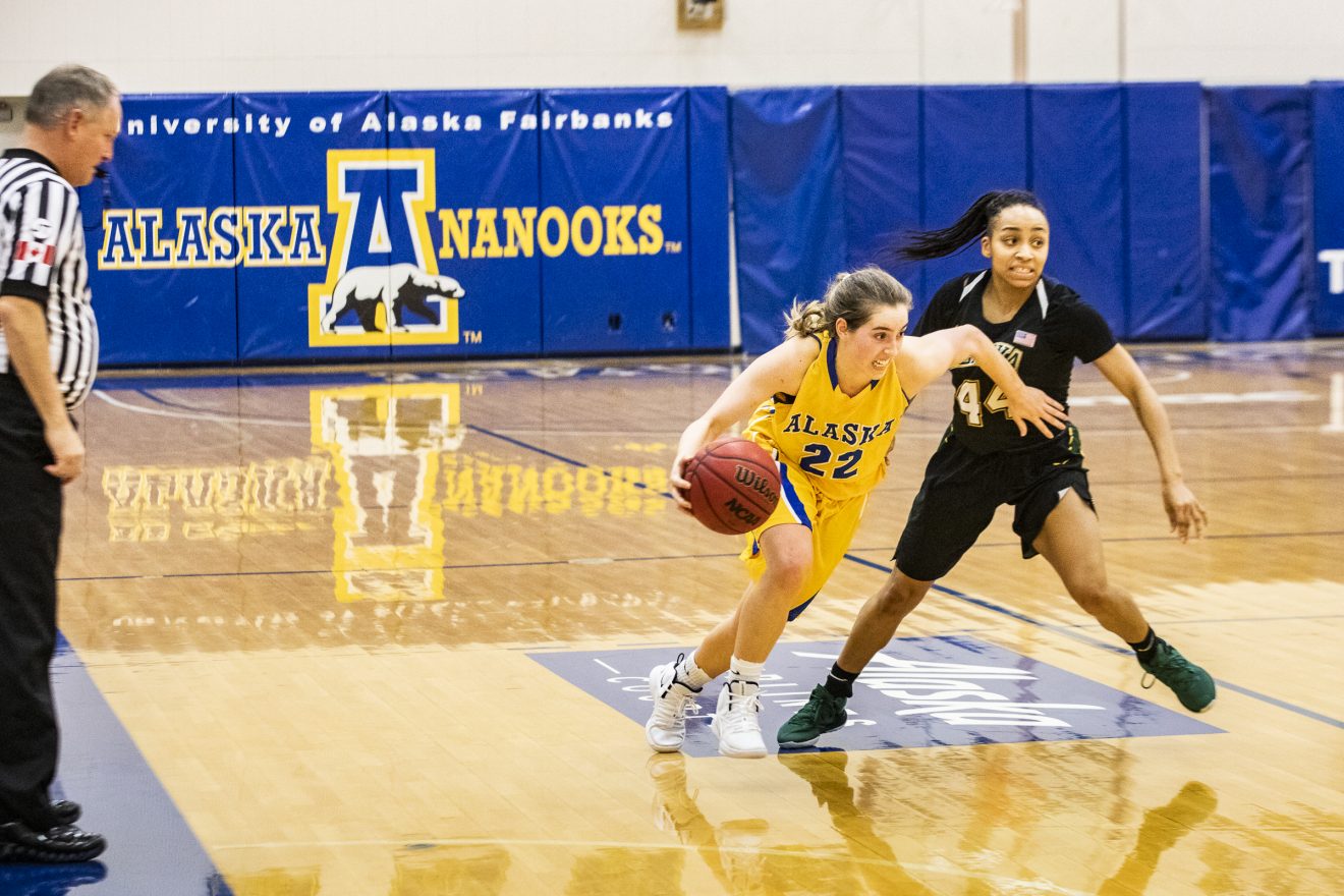 A UAF women's basketball player drives past a UAA opponent.
