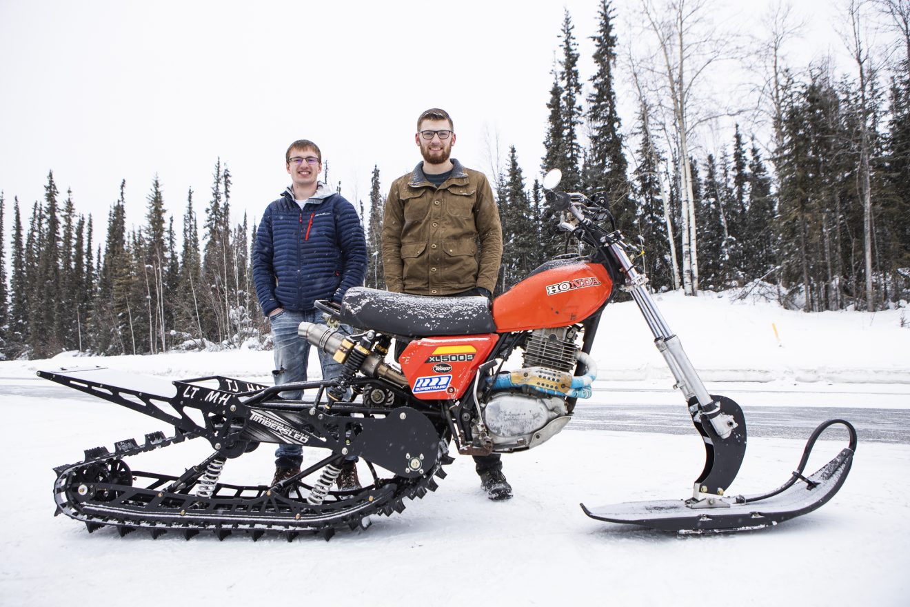 UAF photo by JR AnchetaJordan Osowski, left, and Trevor Norris pose by the snowmachine-motorcycle hybrid they built this winter in the garage of their College Road rental.
