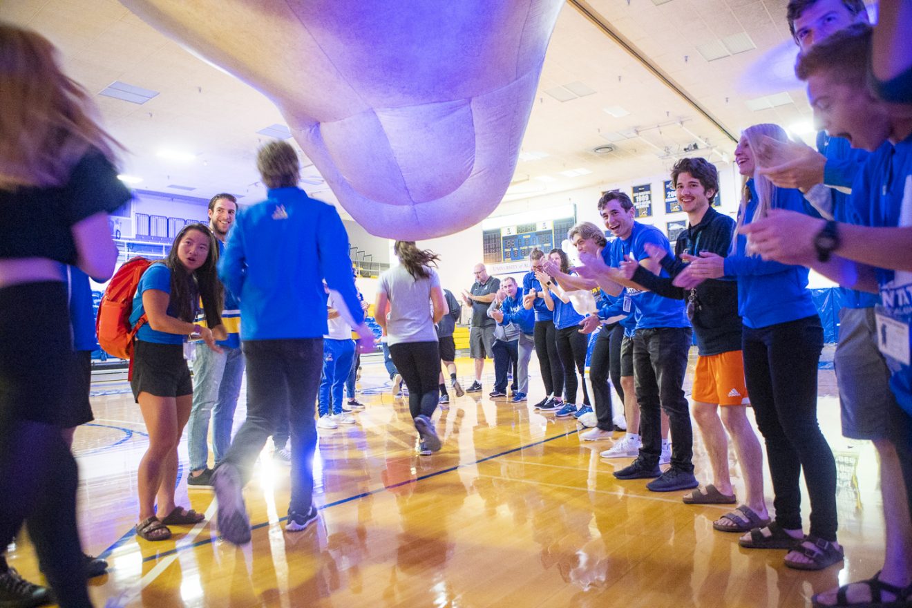Students run between two lines of cheering staff and students as part of orientation.