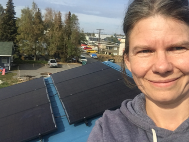 Closeup photo of Michelle Wilber on a roof with solar panels.