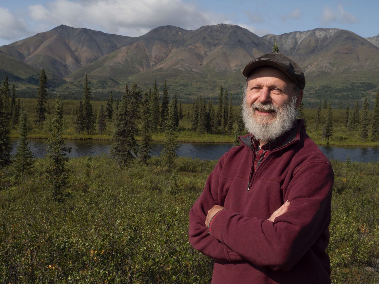 Photo of Terry Chapin standing with mountains, trees and a lake in the background