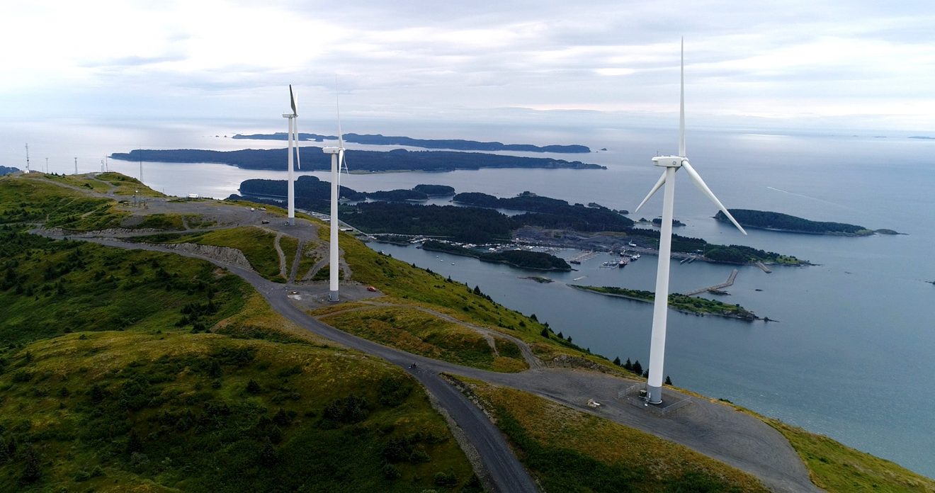 Turbines on a hill overlooking islands and the Gulf of Alaska.