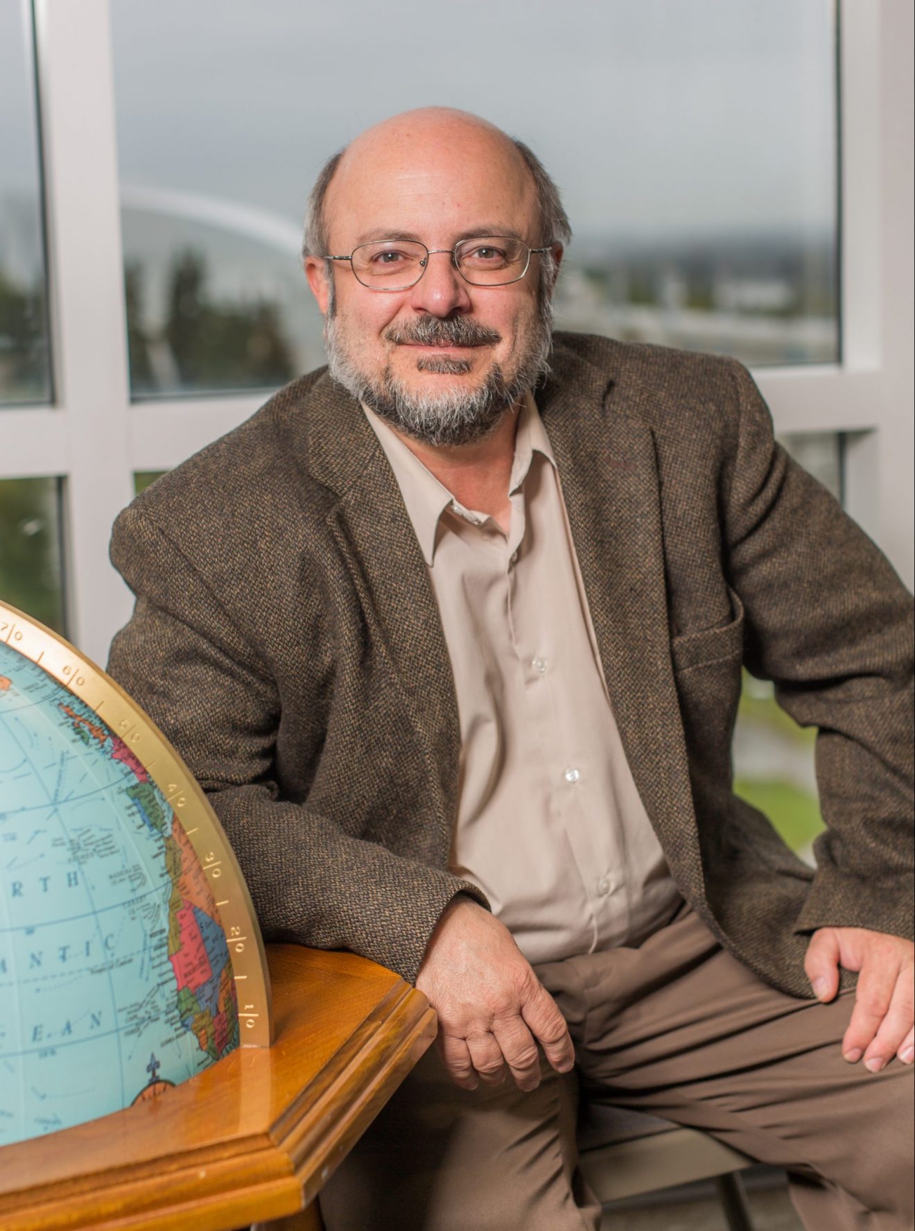Mike Castellini seated beside a globe.