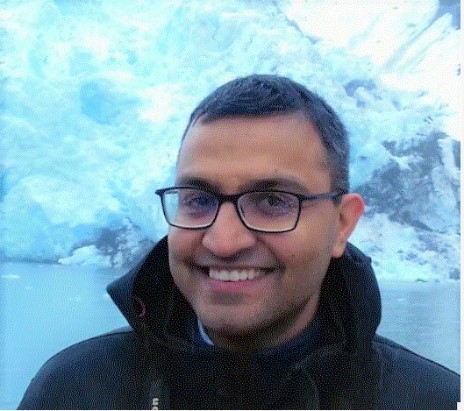 Head shot of Srijan Aggarwal with a glacier behind him.