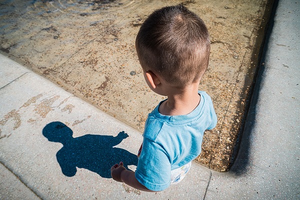 Photo by Arek Socha. A child investigates a shadow during a sunny day.
