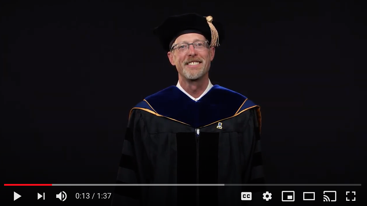 Screen shot of Chancellor Dan White in commencement regalia in front of a black background.