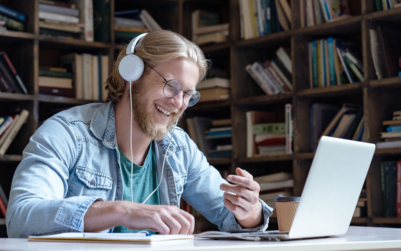 Man wearing headphones and talking to someone on a laptop