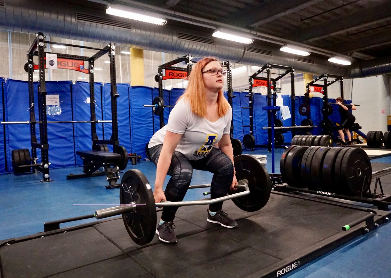 A woman lifts weights in a weight room.