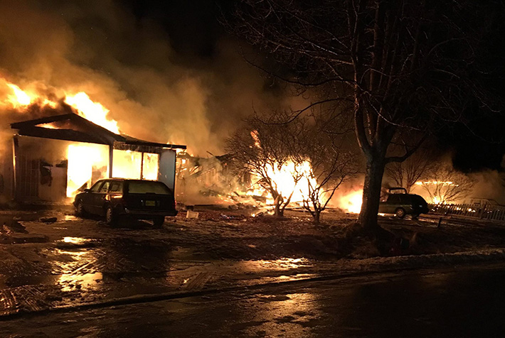 Night-time scene of several houses engulfed in flames.