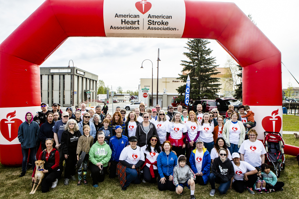 Large group of people, many wearing Heart Walk T-shirts, under an inflatable arch for the Heart Walk